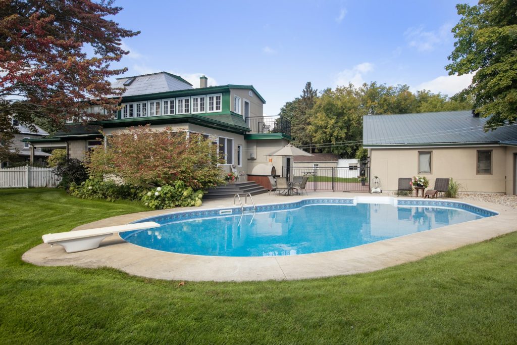 Backyard pool surrounded by lawn behind a home