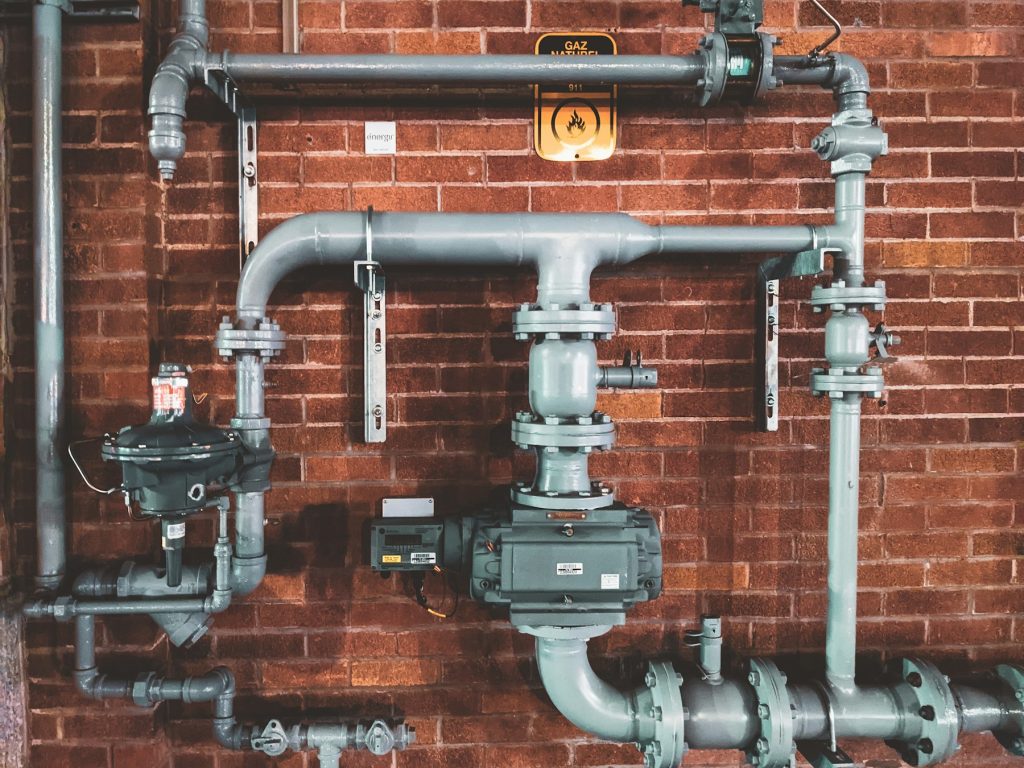 Plumbing pipes and valves mounted on a brick wall